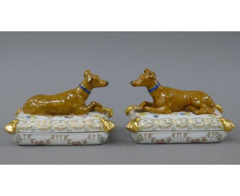 A pair of porcelain trinket boxes each formed as a dog on a cushion. 17.5 cm long.
