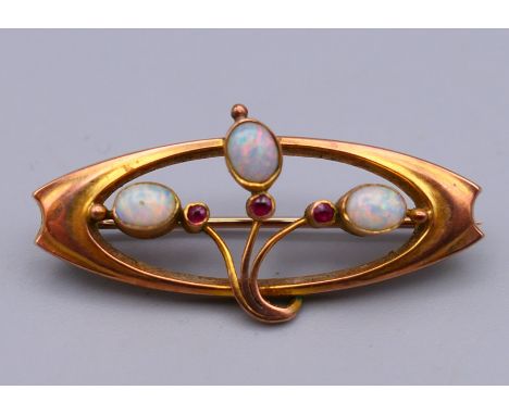 An Art Nouveau 9 ct gold, opal and ruby brooch, boxed.  3.5 cm x 1.5 cm. 1.9 grammes total weight.