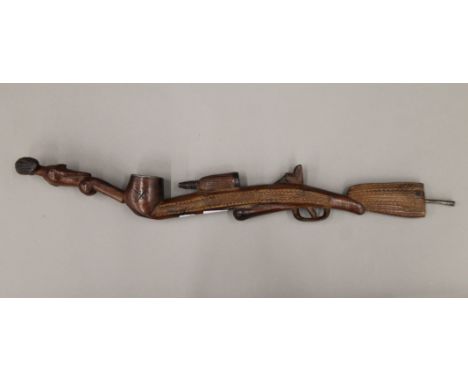 A tribal wooden pipe, carved as a rifle and a nude female. 68 cm long.