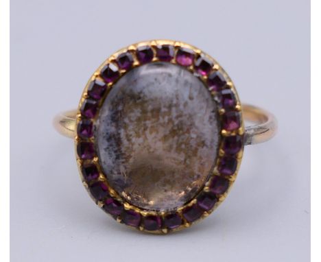 An 18th century unmarked gold mourning ring with oval central setting surrounded with amethysts, the reverse indistinctly ins