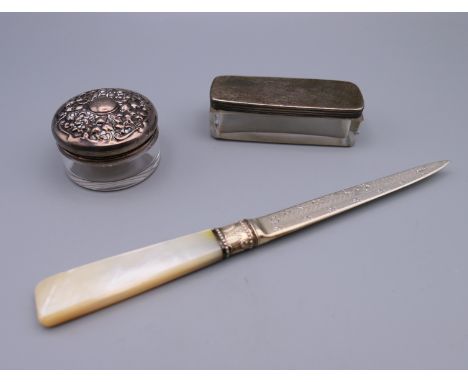 A silver and mother-of-pearl handled paper knife, and two silver topped glass trinket boxes.  Knife 18 cm long, circular box 