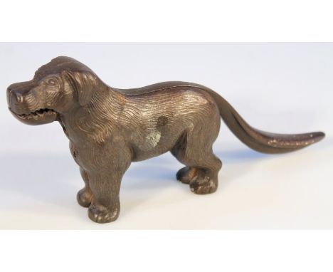 An early 20thC cast metal nut cracker in the form of a standing dog, the tail hinging and articulating to reveal an open mout