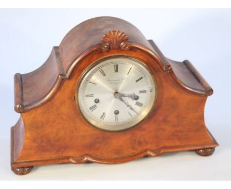 An early 20thC Bravingtons cased mantel clock, with a shaped scroll case centred with a floral finial, with a silvered circul