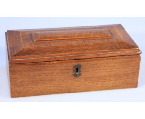 An early 20thC oak tea caddy, of rectangular sarcophagus form, the hinged lid revealing a three sectional interior with exter