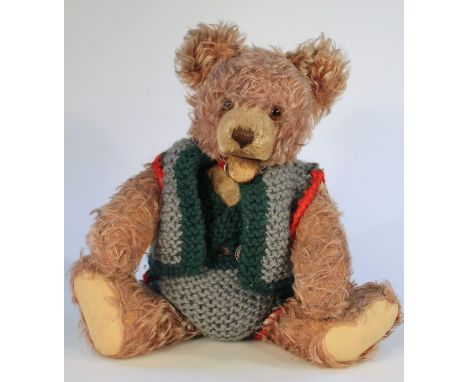 An early 20thC plush teddy bear, in light brown with mouth open and articulated limbs, with velvet pads and (later) knitted o