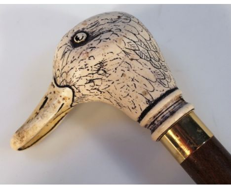 A 20thC walking stick, of cylindrical form with gilt metal tip and mount, headed by a resin duck head, 94cm high.