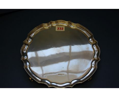 A silver circular tray by James Deakin & Son, Sheffield 1917, having pie crust rim on scroll supports, 25cm, 575g.