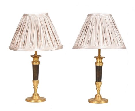 A pair of gilt and patinated metal candlesticks, second half 19th century, later converted to electricity, with two light gre