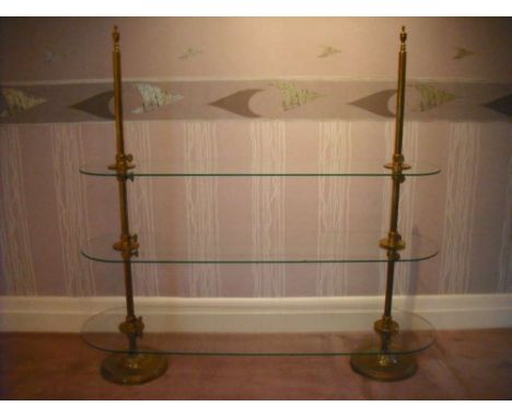 Victorian brass and glass three shelf display stand, the oval glass shelves supported by turned brass columns on circular bas