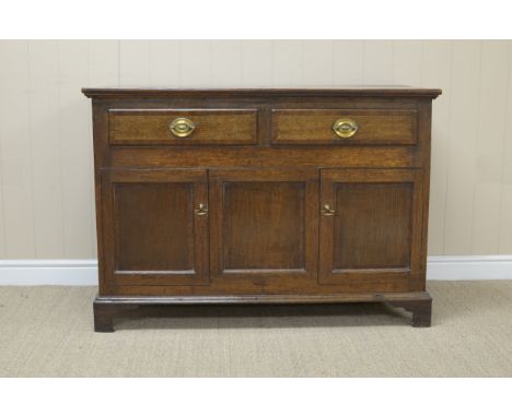 An antique oak small Dresser Base/Side Cabinet fitted two drawers with two panelled doors flanking central panel on bracket f