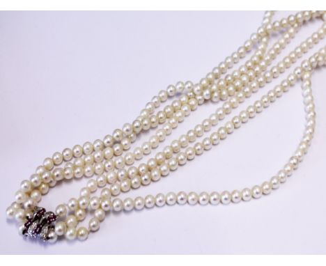 A three string cultured pearl necklace having white metal diamond ruby clasp