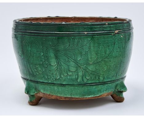 A Chinese green glazed biscuit tripod censer, Ming dynasty, early 17th c, the rounded sides incised with peony meander, on th
