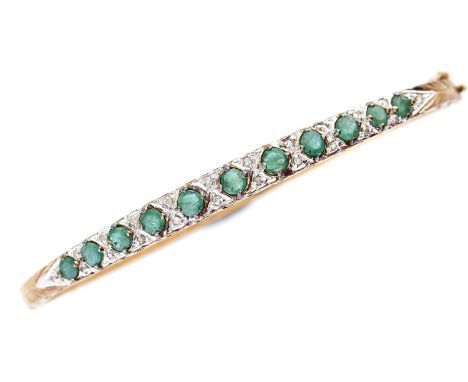 A 9ct gold diamond and emerald bangle, 9.9g  