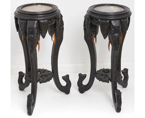 A pair of oriental marble topped ebonised jardinere stands, early 20th c, the circular tops above three elephant mask and tru