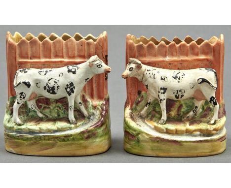 A pair of Staffordshire flatback spill holders in the form of a cow before a fence, late 19th c, 11.5cm h  Part of the fence 