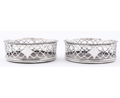 A pair of George III gadrooned silver wine coasters, of openwork form with inset turned mahogany base, 12cm dia, fully marked