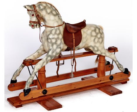 A painted wood rocking horse, mid 20th c, with leather saddle, bridle and reins, on waxed pine stand, 94cm h  Good condition 