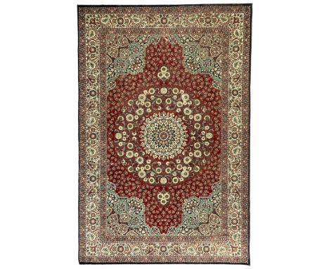 Persian design crimson ground carpet, the central rosette medallion surrounded by scrolling leaves and flower heads, the span