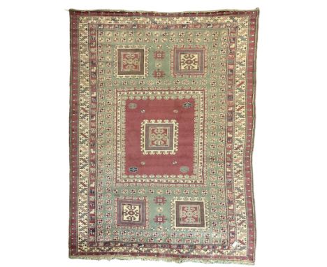 Turkish deep pink and green ground carpet, the square field with hooked borders surrounded by geometric motifs, multi-band bo