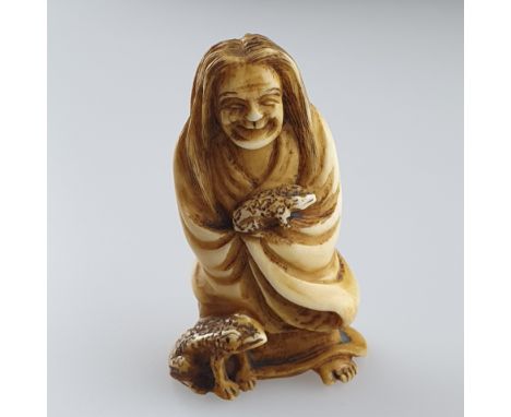 Katabori-Netsuke - Elfenbein, geschnitzt, ziergraviert, schwarz eingefärbte Details, grimassierende Figur mit langer wilder M