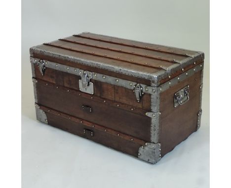 A vintage wooden, metal bound and brass studded cabin trunk, with a hinged lid, and linen lined interior, the lock stamped Bt