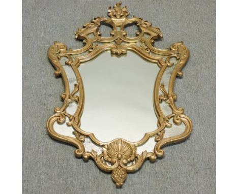 An early 20th century Italian gilt framed wall mirror, of cartouche shape, within a marginal surround, 132 x 67cm