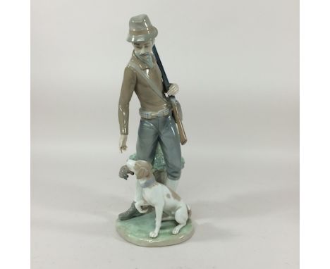 A Lladro figure group of a man holding a rifle, with a dog