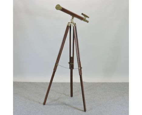 A wood and brass bound floor standing telescope, on a tripod base