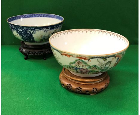 A Chinese famille-rose and blue and white decorated fruit bowl with panels of figures in garden settings, on a carved wooden 