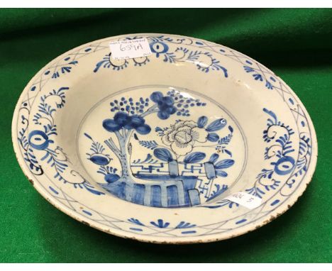 An 18th Century Delft bowl decorated in the chinoiserie style with garden flowers and tree