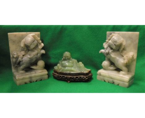 A pair of grey hardstone book ends as Dogs of Fo with balls together with a modern green jade figure of a seated Buddha