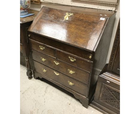 An early to mid 18th Century oak bureau of small proportions, the sloping fall enclosing a basic fitted interior with well ov