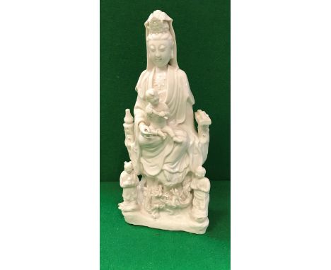 An 18th Century Chinese blanc-de-chine figure of Guan Yin with child upon her knee, dragons and figures at her feet CONDITION