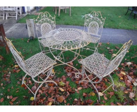 A modern (probably French) painted wrought iron circular garden table and four folding chairs with scrollwork and lattice wor