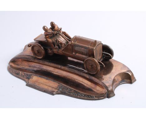 A copper plated pewter motoring desk piece, circa 1905,modelled as car and driver, bonnet opening to reveal two inkwells (one