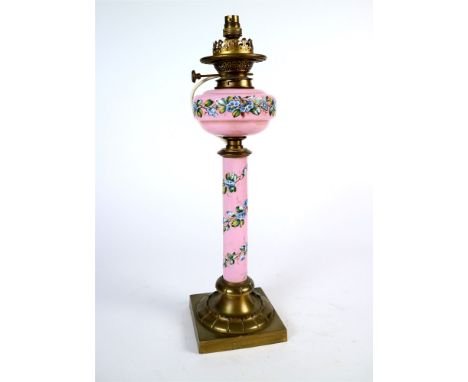A Victorian oil desk lamp (electrified) with a pink opaque glass reservoir and column stem, decorated with hand painted ename