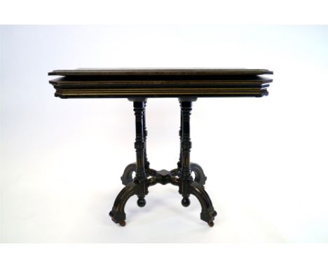 A Victorian Aesthetic movement ebony card table the rectangular canted fold over top enclosing a later lined interior an rais