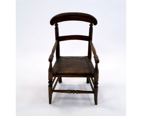 A Victorian child’s elm commode stool with double bar back and pole arms above a hinged seat and raised on ring turned legs j