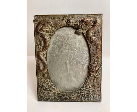 An early 20th century metal photograph frame with embossed decoration of chrysanthemums and a dragon chasing a flaming pearl,