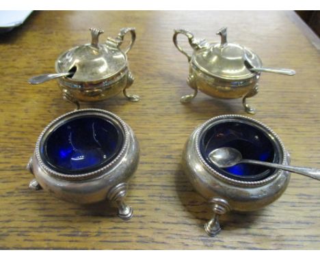 Two Elizabeth II Asprey silver mustard pots with blue glass liners, Birmingham 1989, and later spoons by a different maker, a