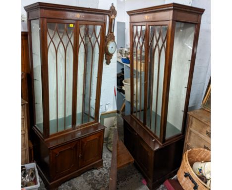 A pair of reproduction mahogany display cabinets having dental moulded cornice, glazed doors, two cupboard doors and bracket 