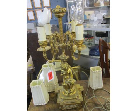 An ormolu table lamp depicting a cherub reading a tablet above a four-branch light holder, with central column holding a bowl