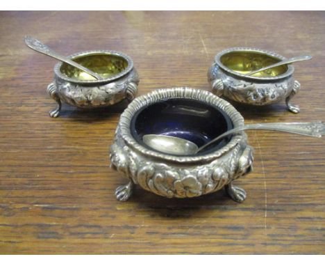 A pair of silver circular salts with fluted turnover top rims and gilded interior, repousse flower head and leaf decoration, 