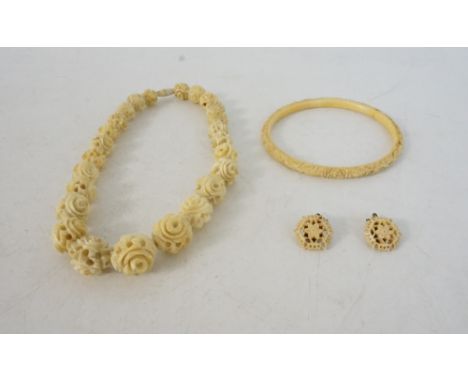 CARVED IVORY GRADUATED FLOWER-HEAD BEAD NECKLACE 
pair of ivory flower earrings and a carved ivory bangle with bird and flora