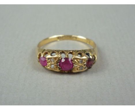 An early 20th Century ruby, diamond and 18ct gold dress ring, the face claw set with three graded rubies, the largest of appr