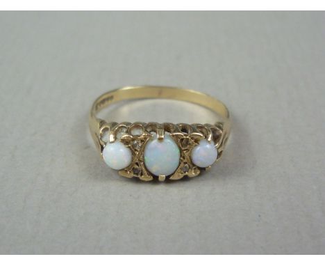 A three-stone opal ring, the opal cabochons divided by pairs of small diamonds, claw-set on 9ct gold, central opal approx 5 x