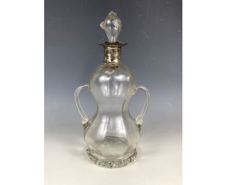 A Victorian silver mounted free blown glass decanter, of waisted and subtly faceted form with a pair of loop handles, the gro