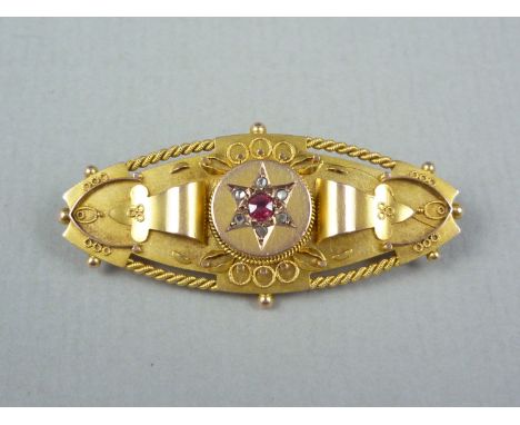 A Victorian diamond, ruby and 9ct gold Etruscan revival brooch, of lenticular form, the gemstones being gypsy set in a star a