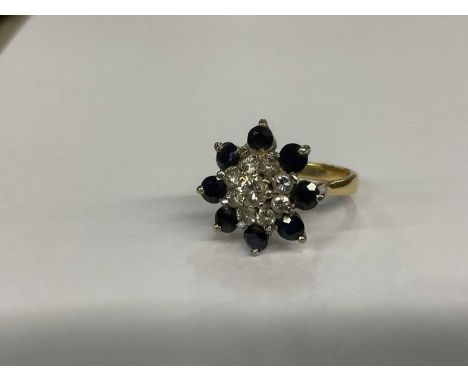 Diamond and sapphire cluster ring with a central floral head cluster of brilliant cut diamonds surrounded by eight round mixe