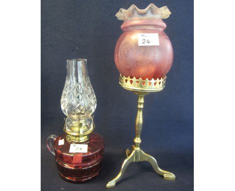 Brass single burner chamber oil lamp with cranberry glass reservoir and cut glass chimney, together with a brass candle light